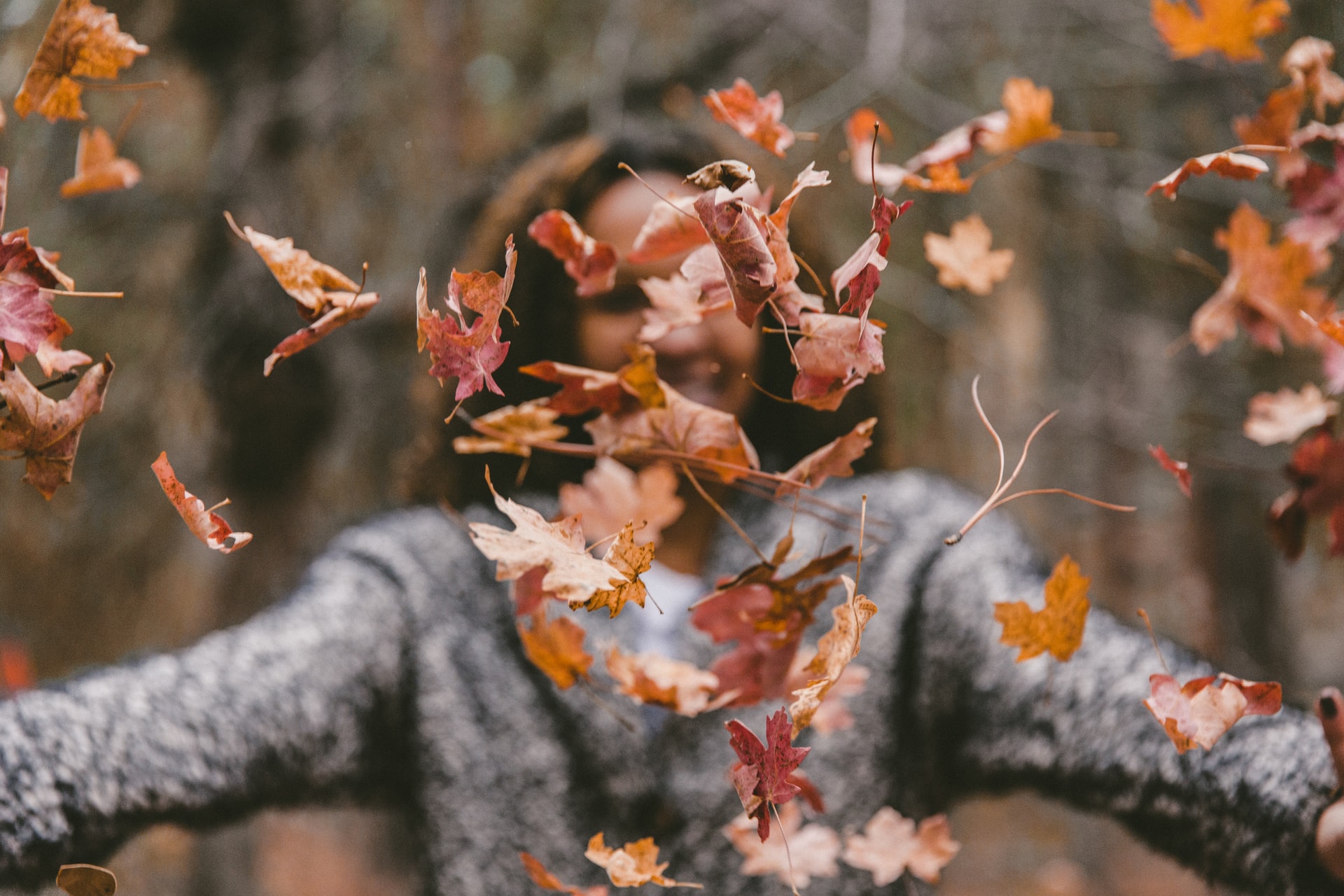 woman throwing autumn leaves